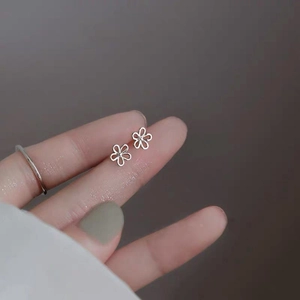 Elegant S925 sterling silver hollow flower stud earrings held on a fingertip