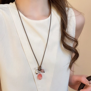 Detail of pink stone pendant on brown wax cord necklace with silver bead accents