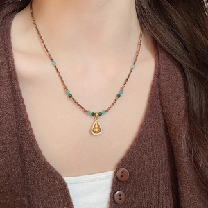 Detail of tiger eye and jade bead necklace with a crystal-embedded gold gourd pendant