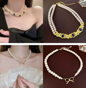 Détail de colliers en perles vintage avec pendentif feuille dorée et nœud sur cuir noir