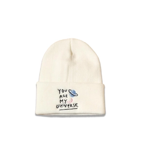 Close-up of You are my universe embroidery on a creamy white knitted beanie hat