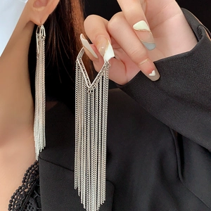 Detail of silver long tassel earrings with geometric diamond frame on a dark suit