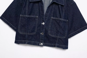Detail of dark blue denim short jacket with white contrast stitching and silver buttons