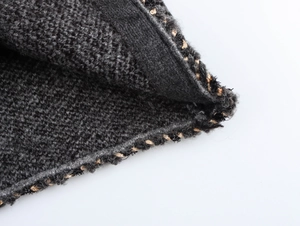 Detailed view of dark grey chunky knit fabric with gold metallic thread accents