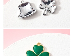 Detail showing alloy clover and hat pendants with green enamel finish on a textured surface