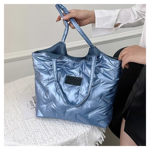 Detailaufnahme der blauen gesteppten Tragetasche mit Metallic-Finish und Logo-Patch