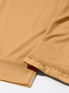 Close-up of ginger yellow jogger pants showing high-density knit fabric and double stitching