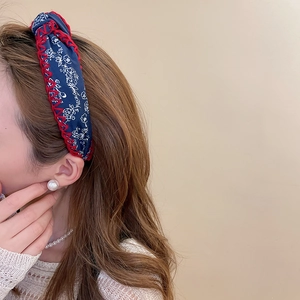 Detailed close-up of floral fabric headband with red crochet edge and pearl earring