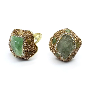 Macro detail of vintage gold rings with green raw stone and crystal borders