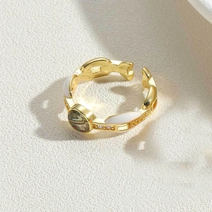 Macro shot of gold adjustable ring with white enamel and colorful swirl center detail