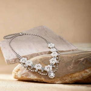 Close-up of silver-tone floral necklace with pearls and crystal teardrop on stone