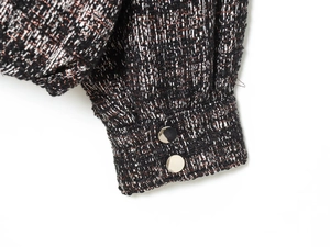 Macro detail of metallic tweed jacket cuff with silver buttons and woven texture
