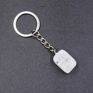 Detail of a natural white crystal keychain with silver ring on a textured dark surface