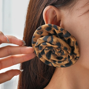 Close-up of a large fabric flower earring with leopard print on a female model