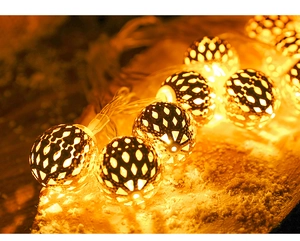 Detail of warm white LED metal hollow sphere lights on a snowy wooden surface