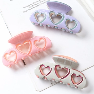Detailed view of hollow heart hair claws in purple, pink, and beige resin finishes