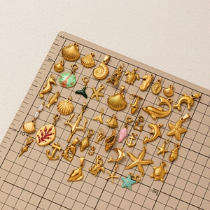 18K gold plated stainless steel ocean charms including starfish and seashells on grid mat