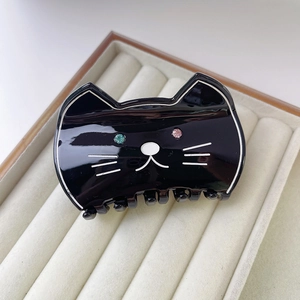 Détail d'une pince à cheveux chat noire en acétate avec strass dans un coffret beige