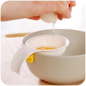 Action shot of egg white separator with yellow hook straining yolk over a bowl