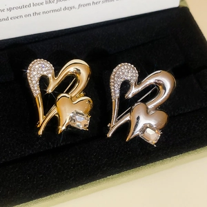 Detail of gold and silver overlapping heart brooches with rhinestones in black velvet box