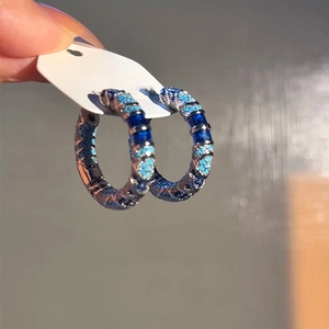 Detail of silver hoop earrings with blue crystal inlay and woven texture finish