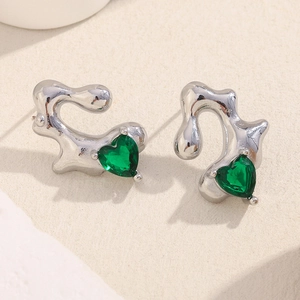 Irregular silver fluid metal earrings with green heart-shaped gemstones on beige base