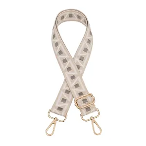 Detail of adjustable geometric patterned bag strap with golden metal lobster clasps