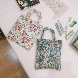 Vue de dessus de deux sacs cabas en toile fleurie avec boutons-pression sur surface matelassée