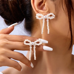 Detailed view of pearl bow earring and matching ring set on a fashion model