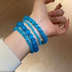 Close-up of four blue cat's eye bead bracelets showing silky luster and varying bead sizes
