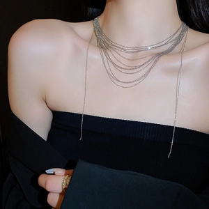 Dettaglio di una collana a catena d'argento a strati con ciondolo su collo di modella