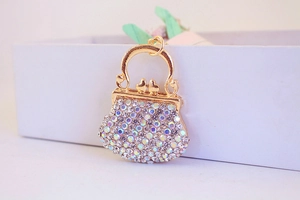 Close-up of golden rhinestone handbag keychain with bird details on white gift box
