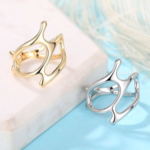 Close-up of gold and silver fluid abstract rings on a marble stand with feathers