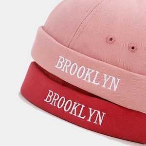 Detail of embroidered Brooklyn letters on brimless docker hats in pink and dark red