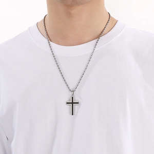 Détail d'un pendentif croix en acier argenté avec incrustation noire sur chaîne torsadée