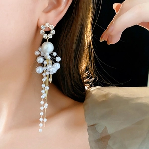 Detail of floral earring with crystal petals, large pearl and long golden chain tassels