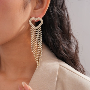 Close-up of golden tassel heart earrings with rhinestones on a model for a luxury look