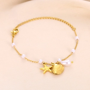 Detail of gold starfish and shell charms with white pearls on a fine metal chain necklace