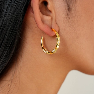 Dettaglio orecchini a cerchio ritorti a forma di C placcati oro 18k con zirconi pavé