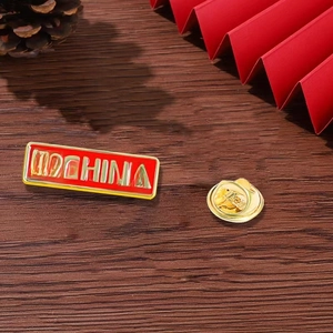 Detail of I Love China enamel pin with butterfly clutch on a rustic wooden background
