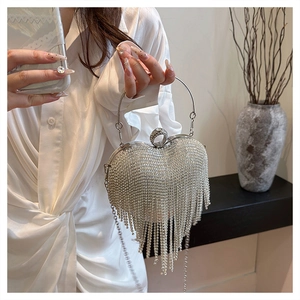 Macro detail of silver heart-shaped evening bag with sparkling rhinestones and long tassels