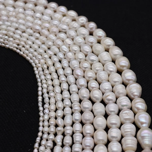 Detailed view of white oval freshwater pearls in various sizes on black background