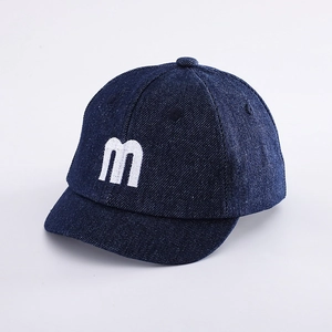 Detailed macro of kids denim baseball cap featuring white M letter embroidery