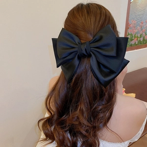 Large black satin bow hair clip worn by a model showcasing its elegant French style
