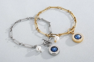 Close-up of gold and silver steel bracelets with blue round charms and white pearls