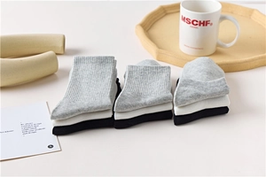 Three-pack cotton socks set in black, white, and grey with textured ribbed cuffs