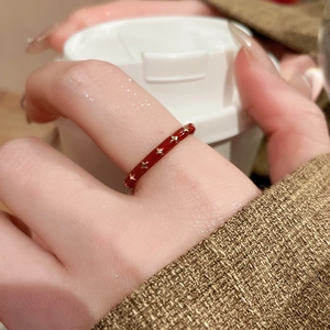Detail of a 14k gold plated red enamel ring with star pattern on woman's finger