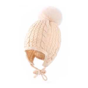 Detailed knit texture of beige baby winter hat with soft faux fur pom and ear flaps