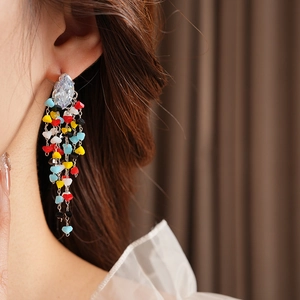 Macro detail of rhombus zircon silver earrings with colorful beaded tassel fringe