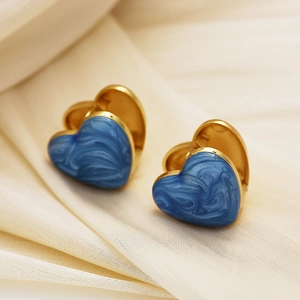 Détail de créoles en forme de cœur avec émail marbré bleu et finition dorée sur satin
